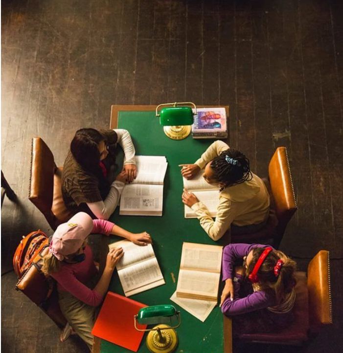 Crianças estudando juntas ao redor de uma mesa.